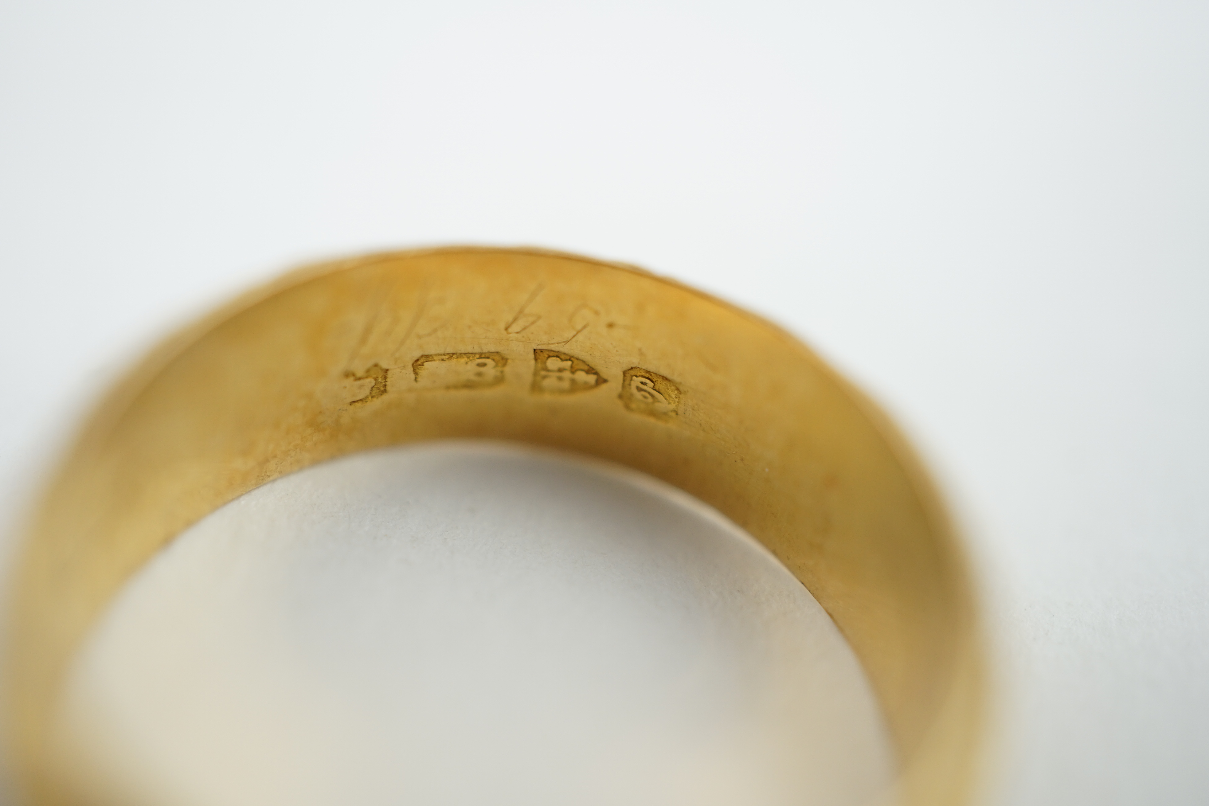 A George V engraved 18ct gold band, size M/N, together with two three or two colour 18ct gold bands